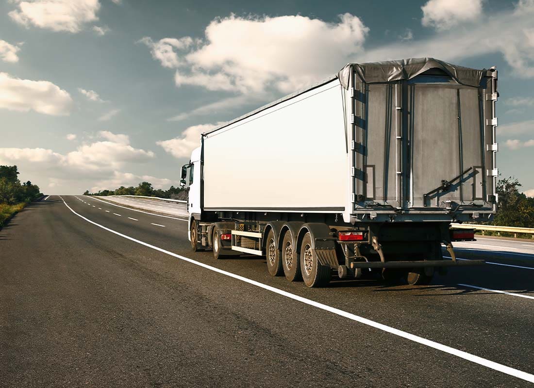 Trucking Insurance - View from the Rear of the Truck Traveling up the Road to Complete a Delivery at Dusk